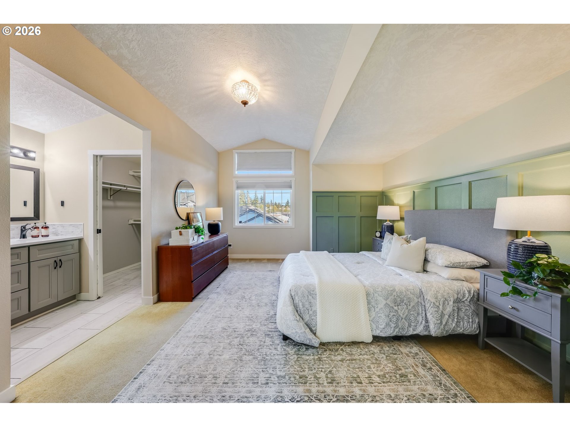 Primary bedroom with a vaulted ceiling, green paneled walls, and an open walk-in closet.
