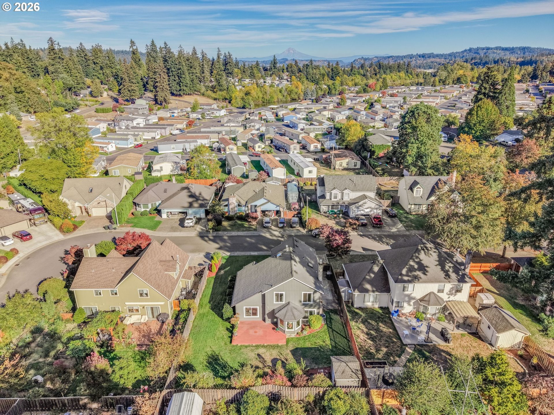 Aerial view of a two-story home with a red patio and fenced backyard, surrounded by neighborhood homes.