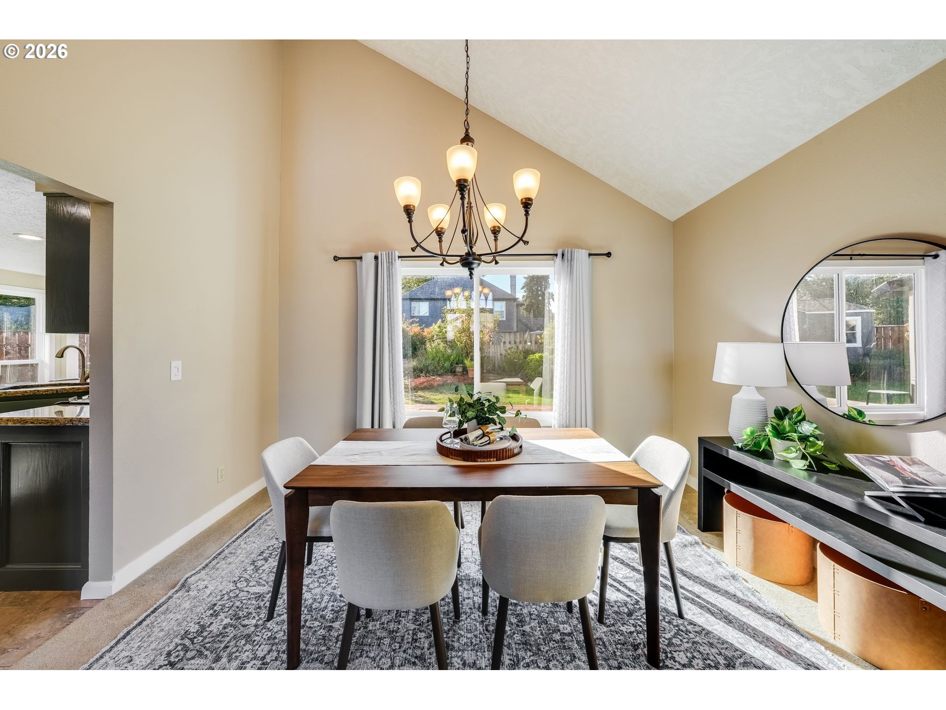 Dining room with a vaulted ceiling, chandelier, dark wood table and garden-facing sliding glass door.