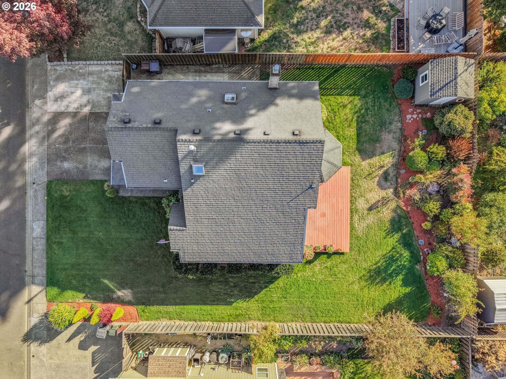 Aerial view of the home, fenced lawn, landscaped garden, and adjoining decks.