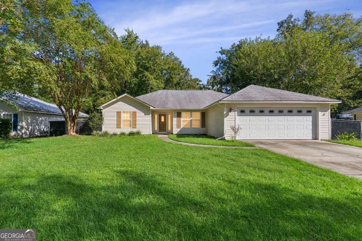 Single-story home with an attached two-car garage, broad lawn, and mature trees.