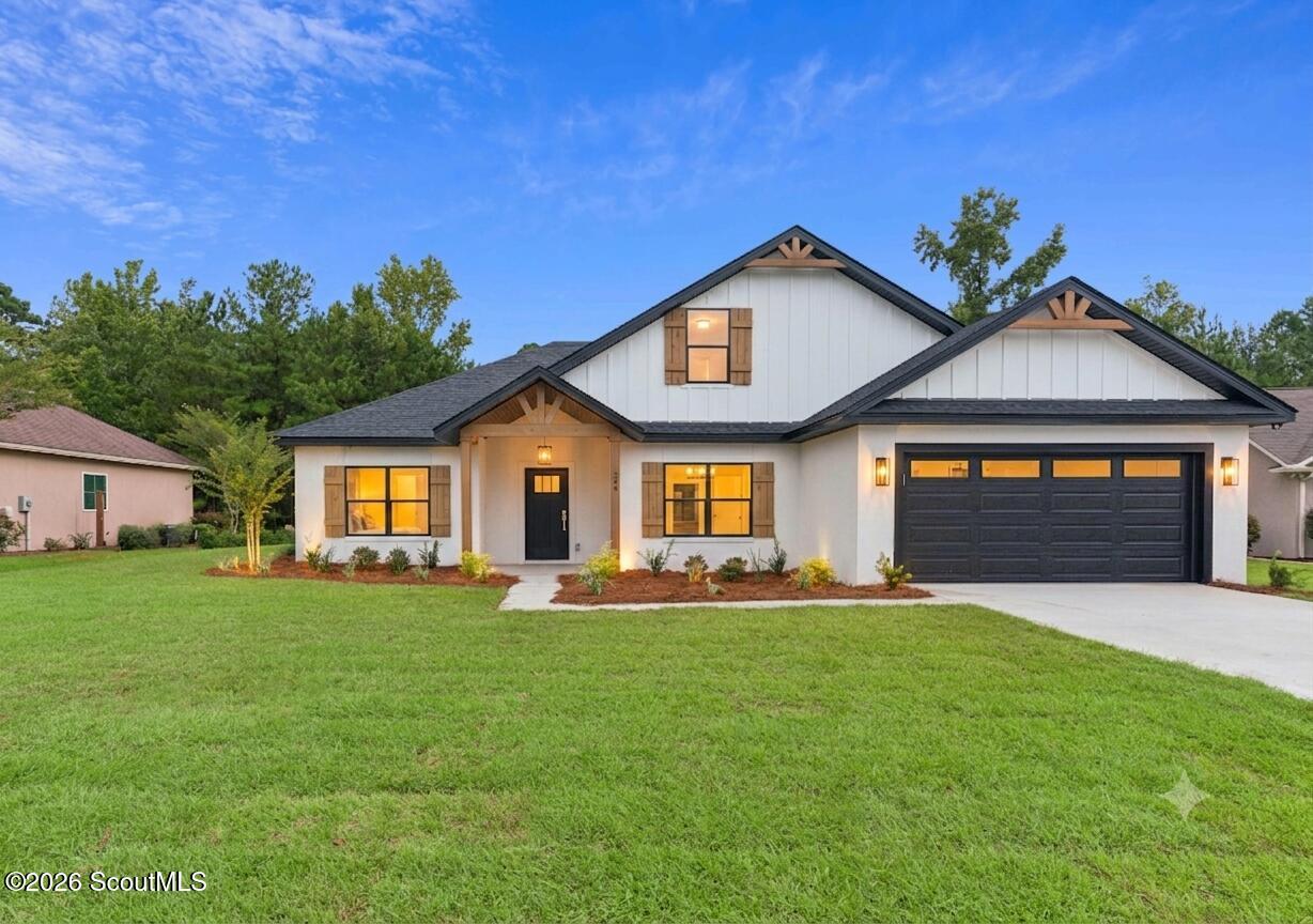 White single-story home with dark gabled roofs, wood shutters, and a black double garage door.