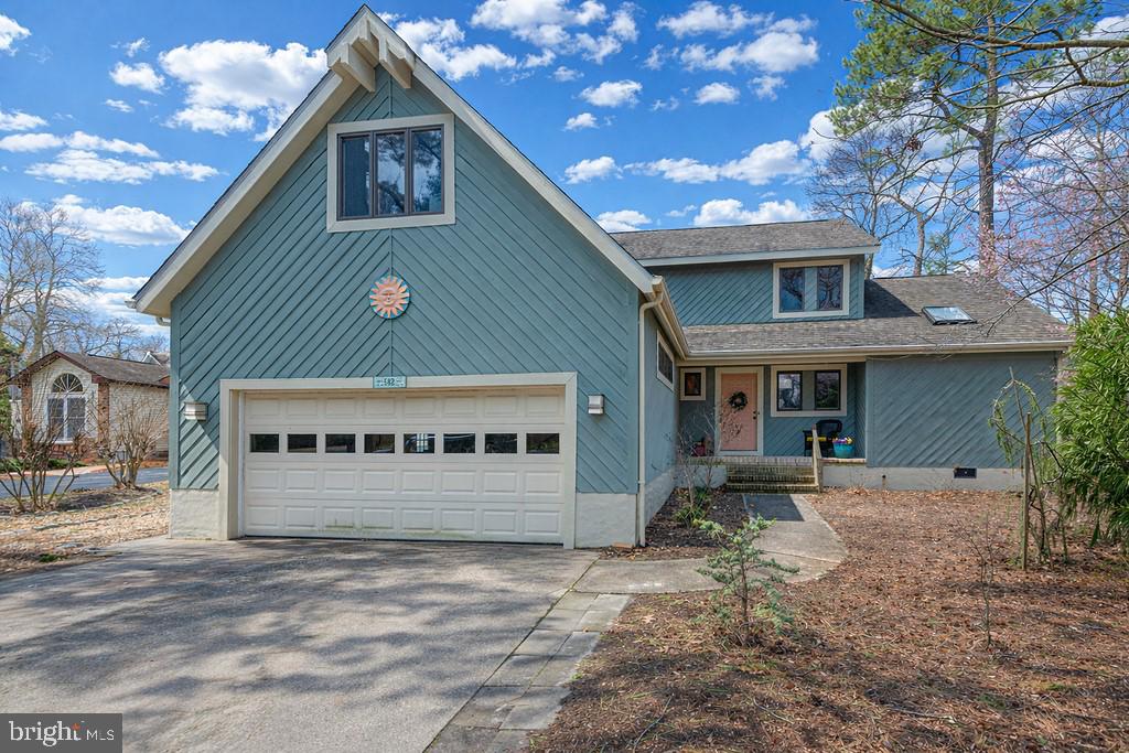 Teal-blue house with a large attached garage, steep front gable, and pink entry door.