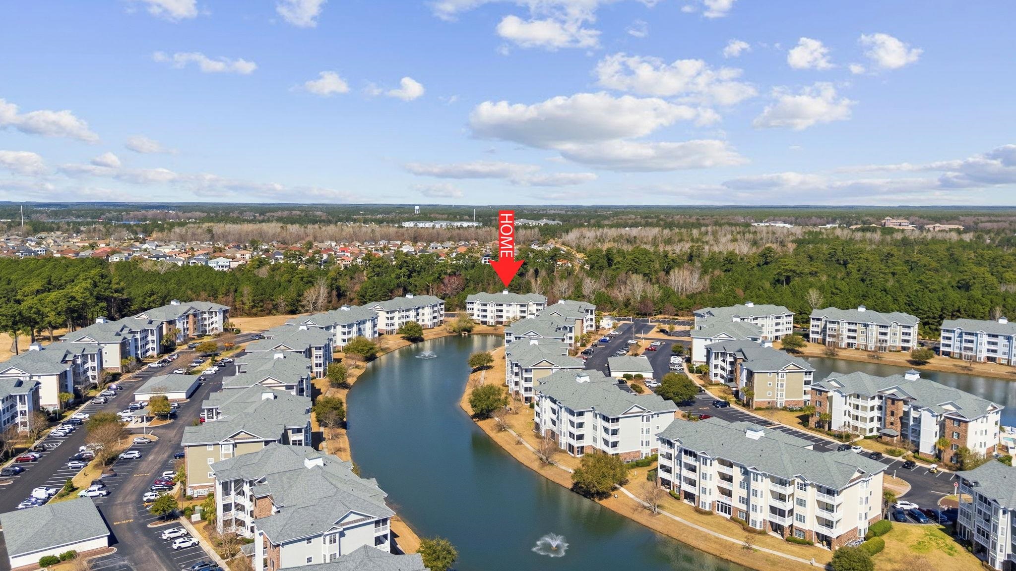 Condominium community around a pond, with a red “HOME” arrow pointing to one building.