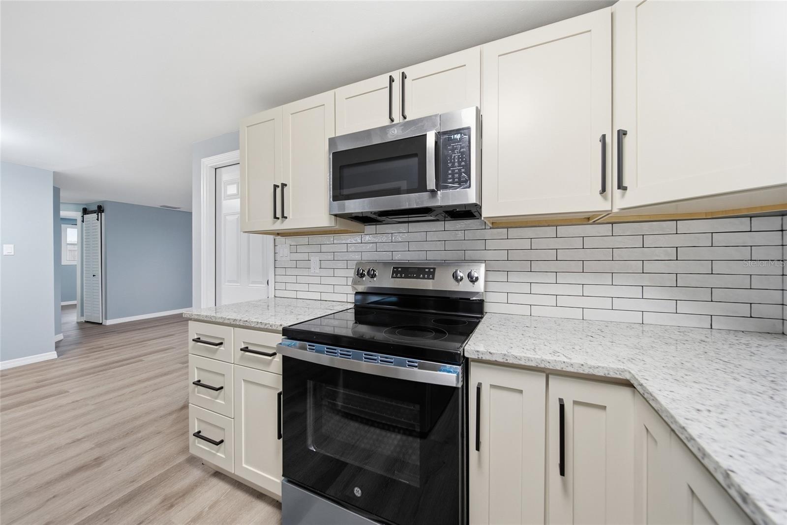 Renovated kitchen with white cabinets, subway tile backsplash, and stainless steel appliances.