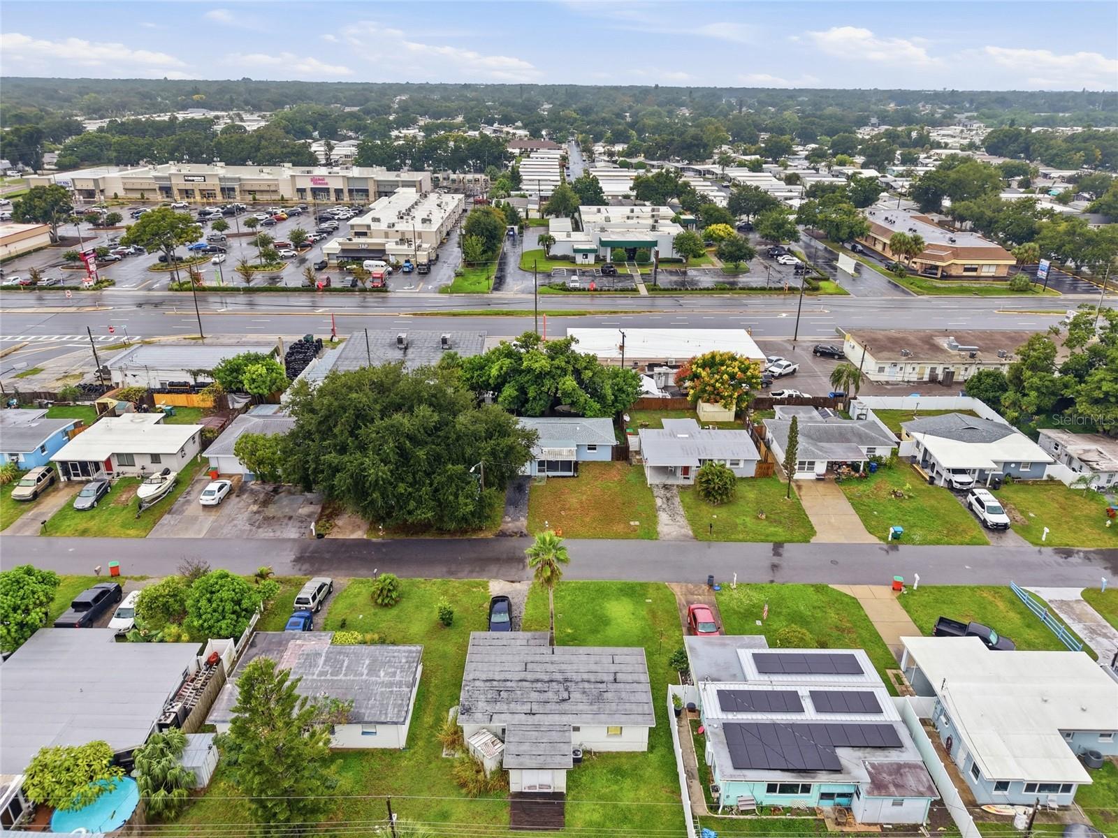 Aerial view of homes with solar panels beside a commercial strip and busy road.
