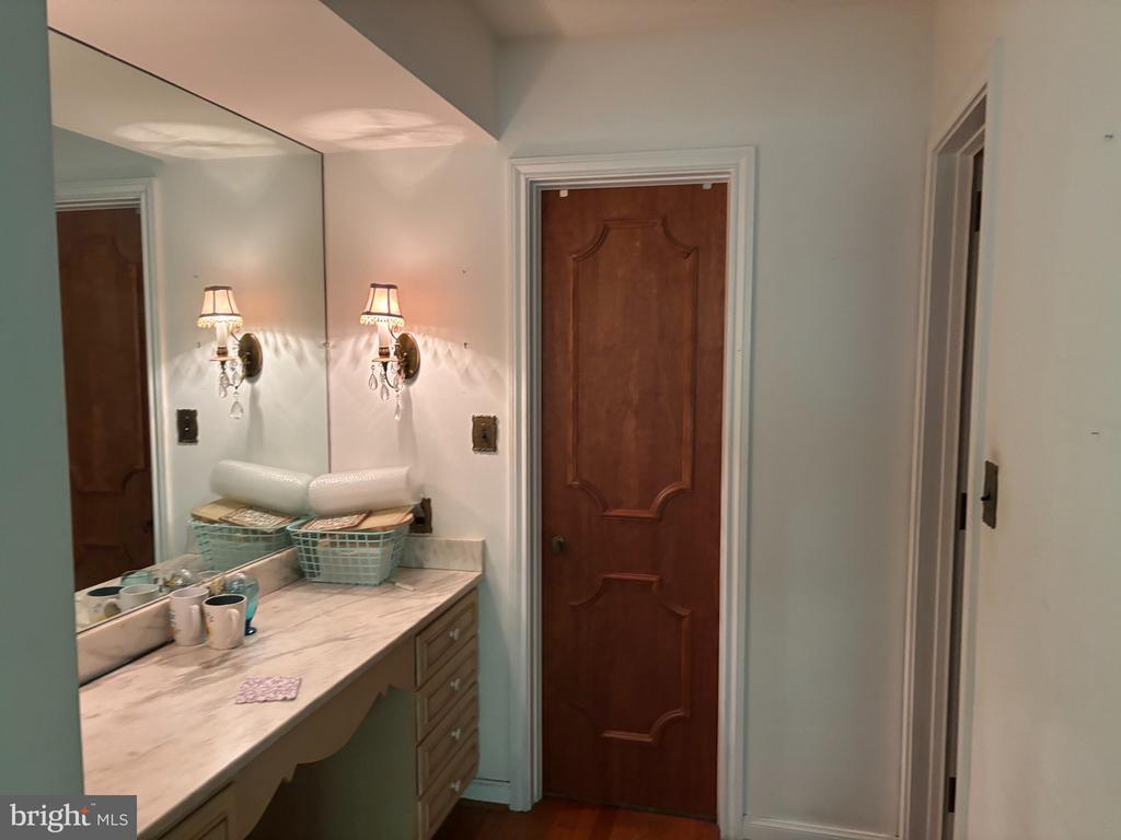 Bathroom vanity with a marble countertop, large mirror, and paneled wooden door.