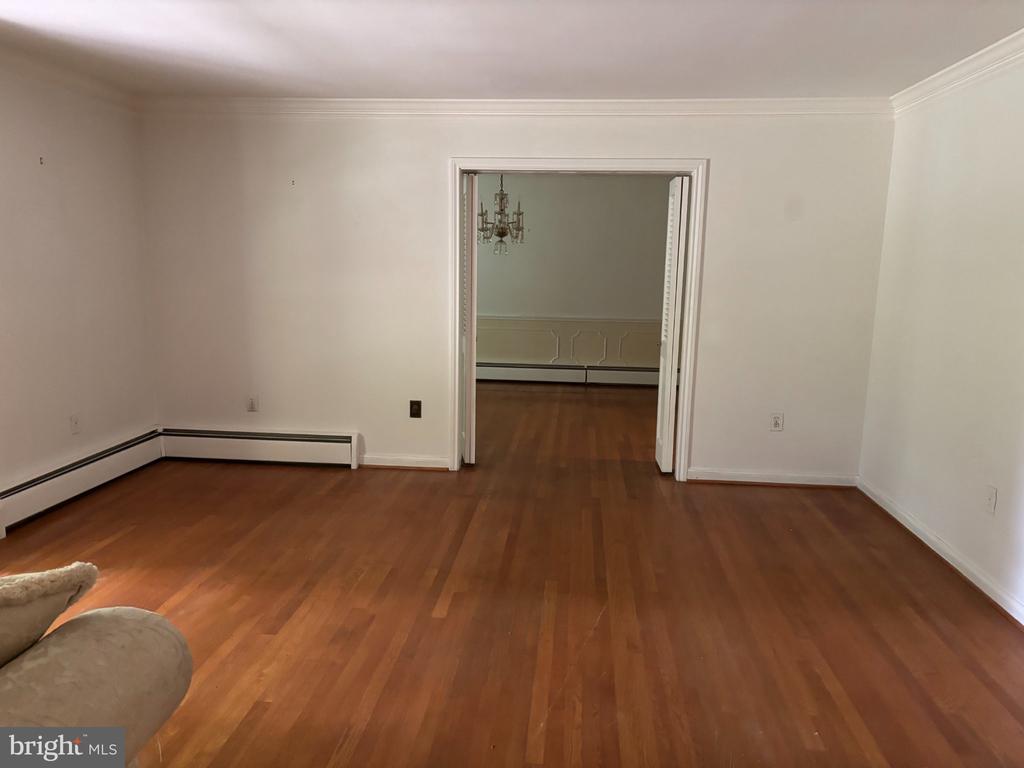 Living room with hardwood floors and a wide doorway opening to a second room.