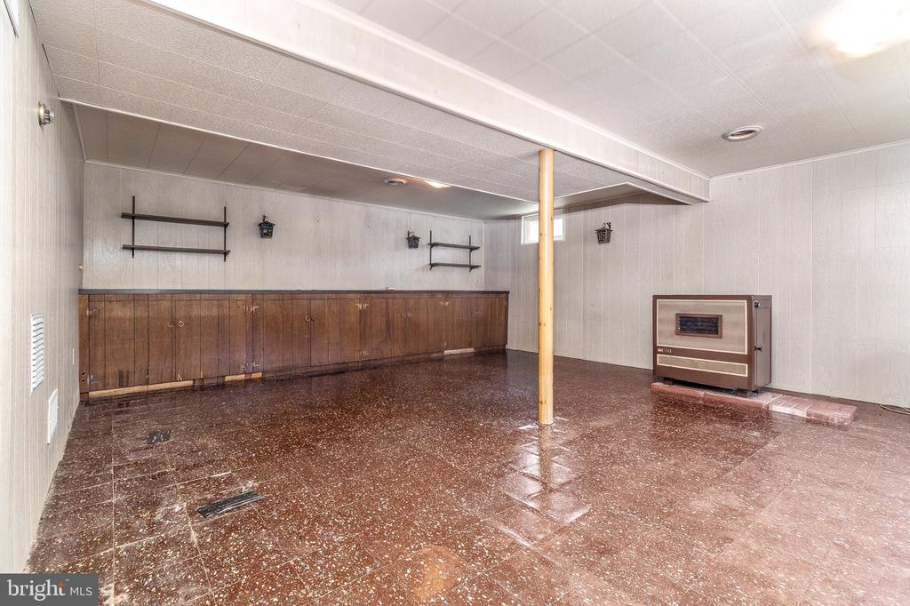 Basement room with built-in wood cabinets, brown tile flooring, and a freestanding heater.