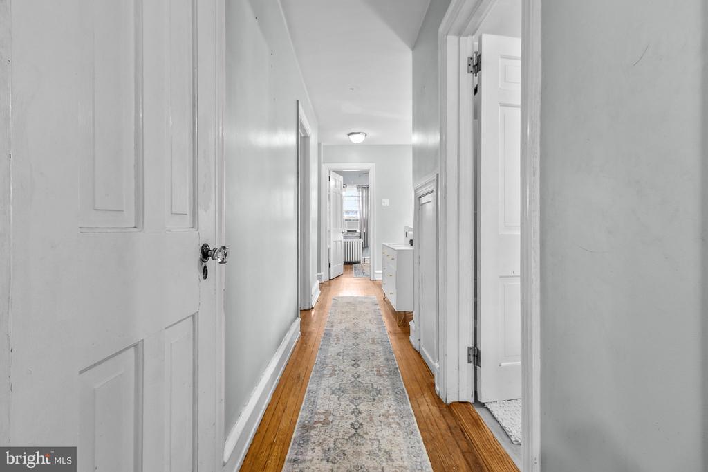 Hallway with white paneled doors, hardwood floors, and a patterned runner.