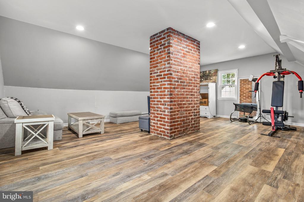 Finished basement with a brick pillar, sitting area, and exercise equipment.