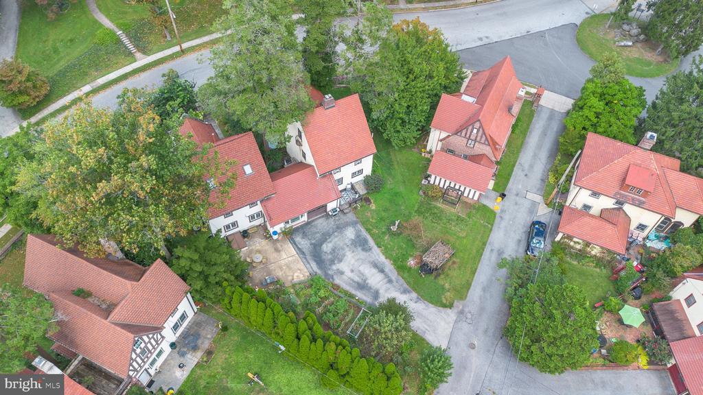 Aerial view of red-roofed homes and a tree-lined residential street with driveways.