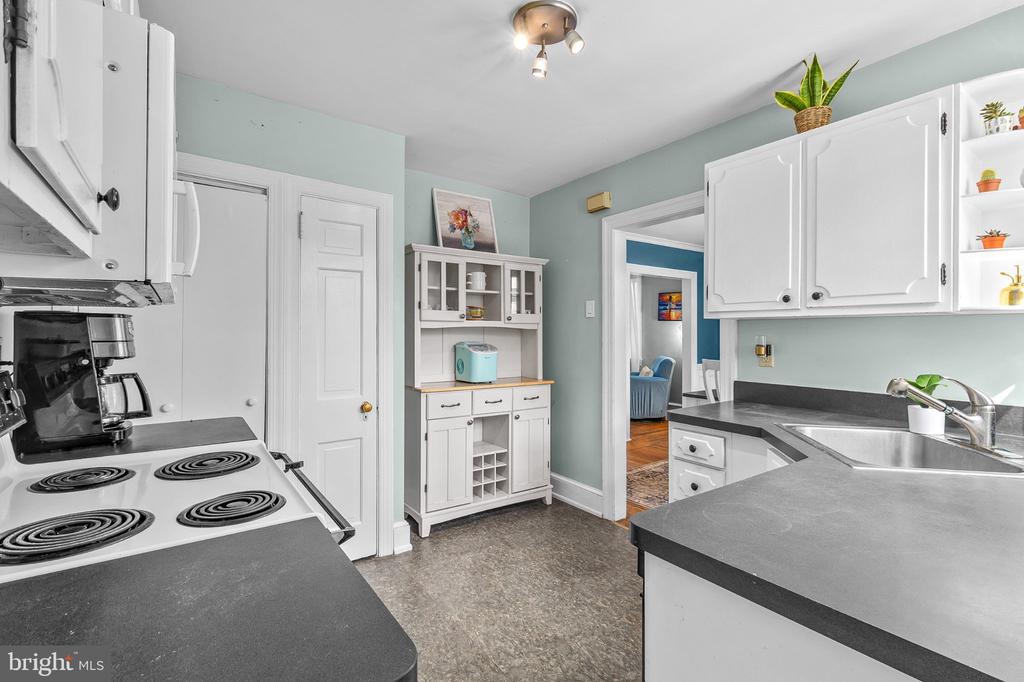Kitchen with white cabinets, dark counters, an electric range, and a stainless steel sink.
