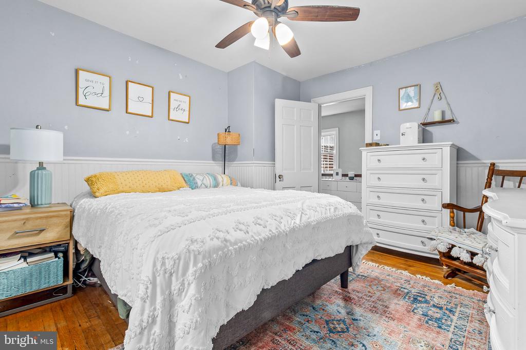 Bedroom with white bedding, yellow pillows, and a white dresser.