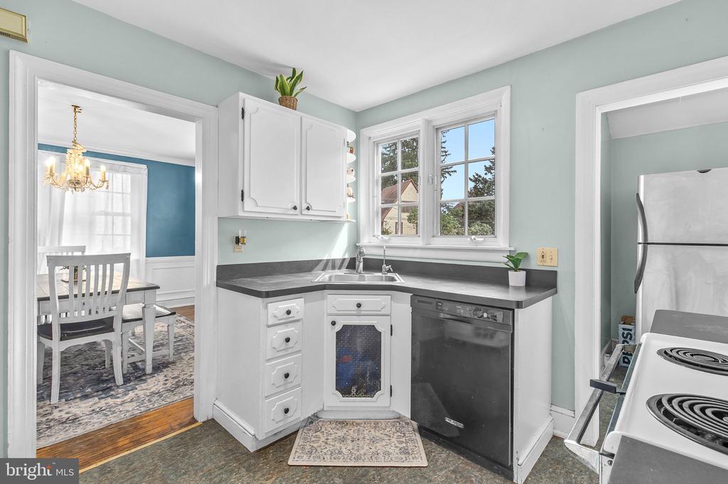 Kitchen with white cabinets, dark countertops, and a sink beneath a sunny window.