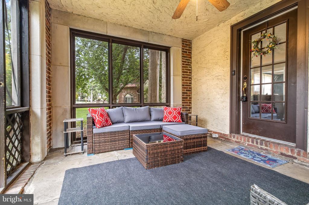 Covered front porch with wicker seating, large windows, and a dark glass-paneled entry door.