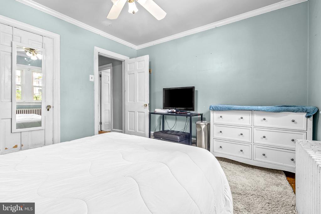 Bedroom with pale blue walls, a white bed and dresser, and a ceiling fan.