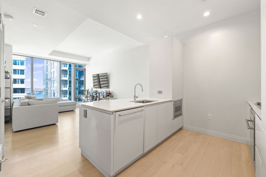 Open-plan kitchen with a large island, adjoining living area, and floor-to-ceiling windows.