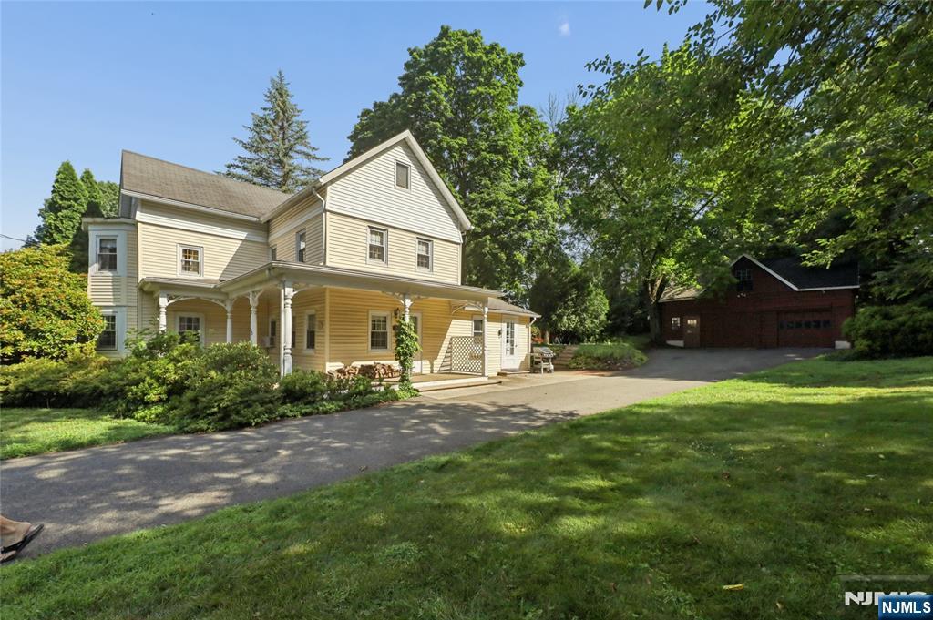 Pale yellow two-story house with a covered porch and detached red garage.