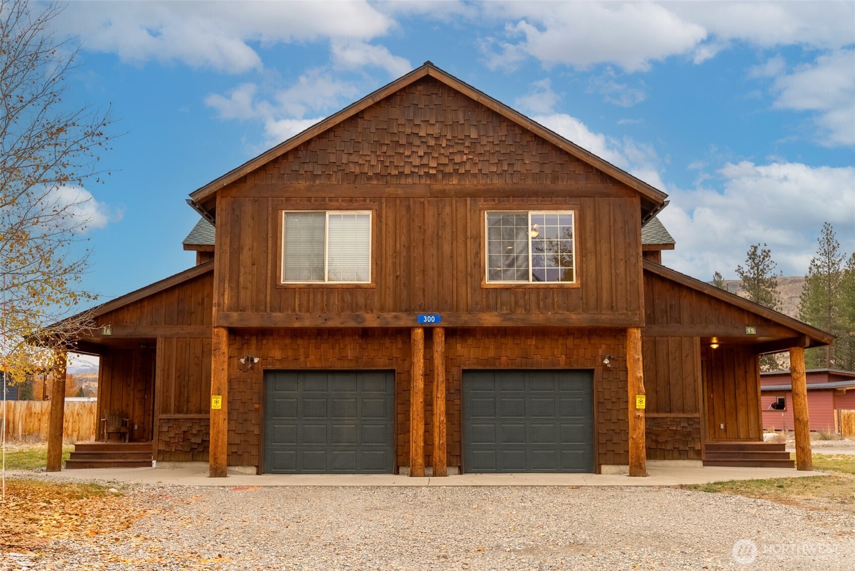 Wood-sided duplex at 300, with two garage bays and covered porches.