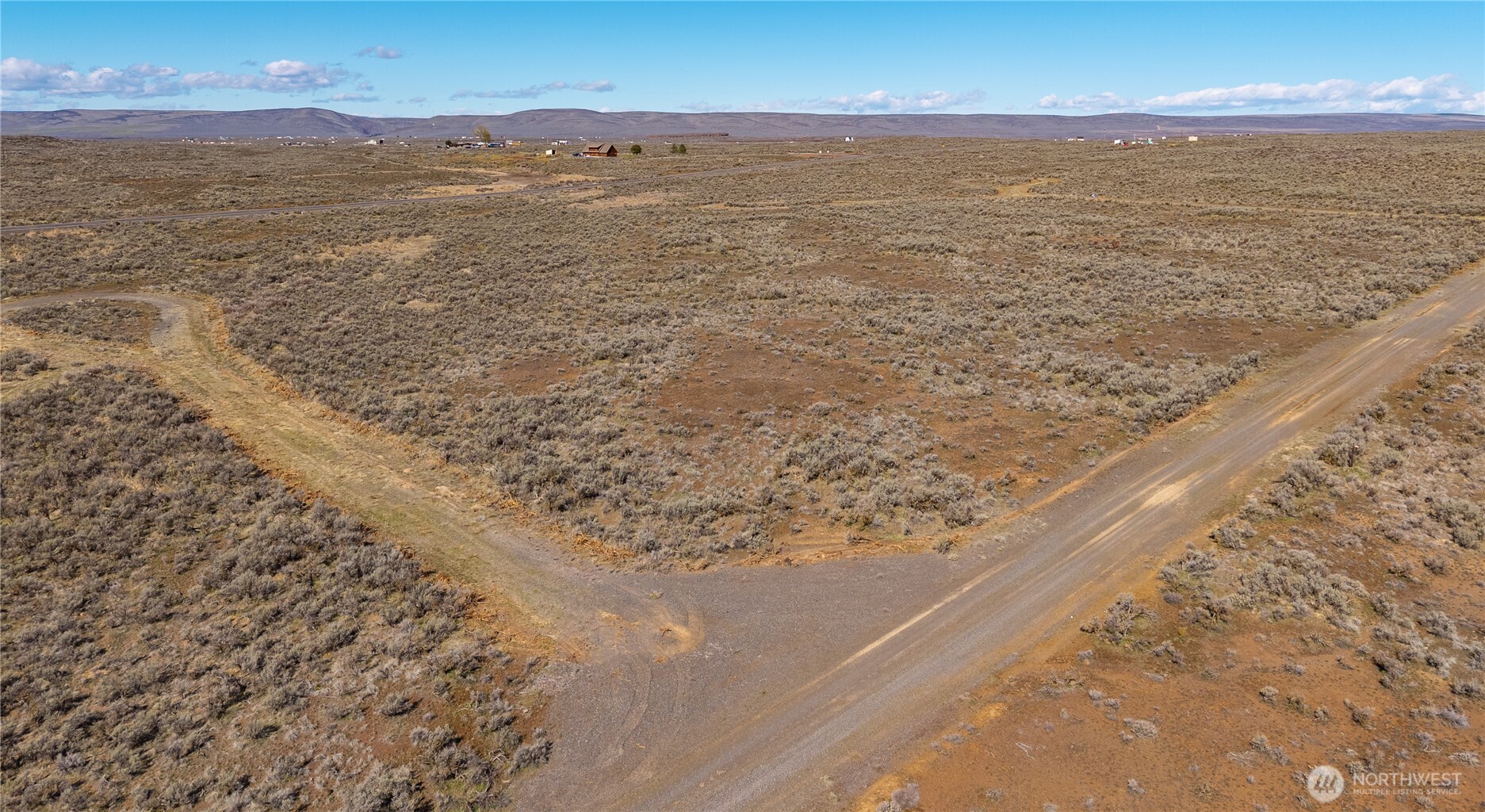 Aerial view of a dry scrubland lot, with curving dirt roads and low hills on the horizon.