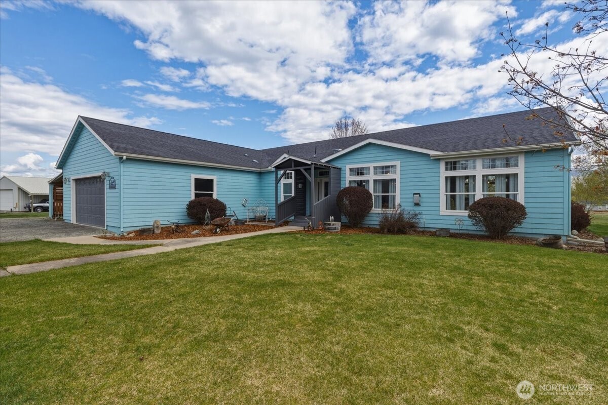 Light-blue single-story house with an attached garage, covered entry, and broad front lawn.