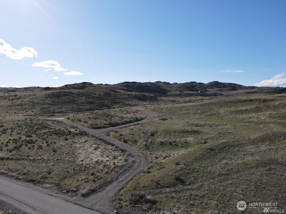 Vacant scrubland parcel with winding dirt tracks and low hills beyond.