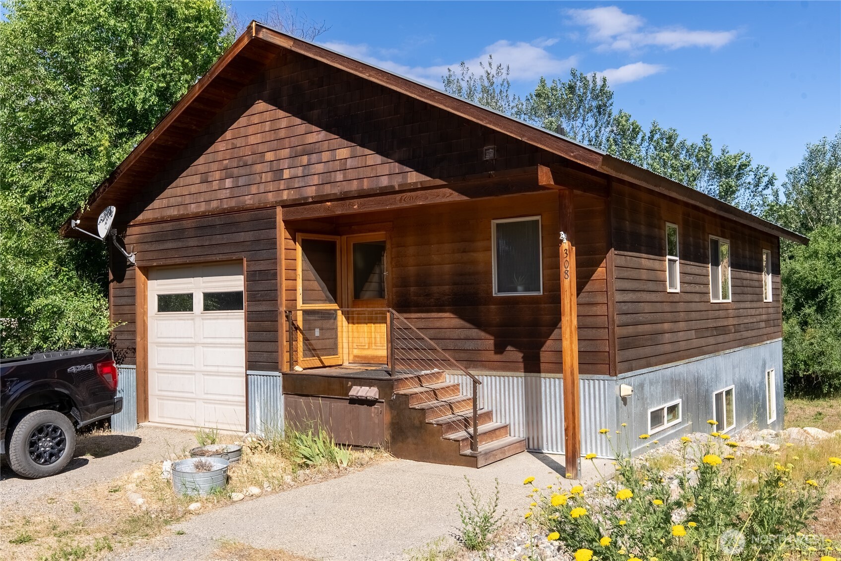 Wood-sided home numbered 308, with a covered porch, metal stairs, and attached garage.