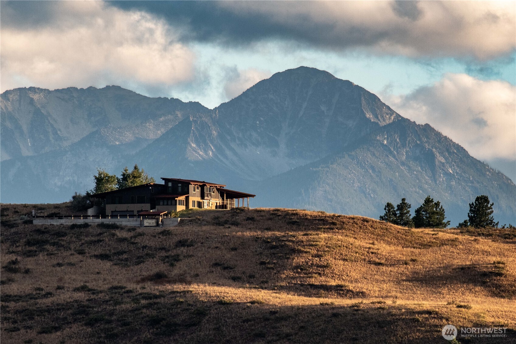 Modern hillside home with a mountain backdrop and warm evening light.