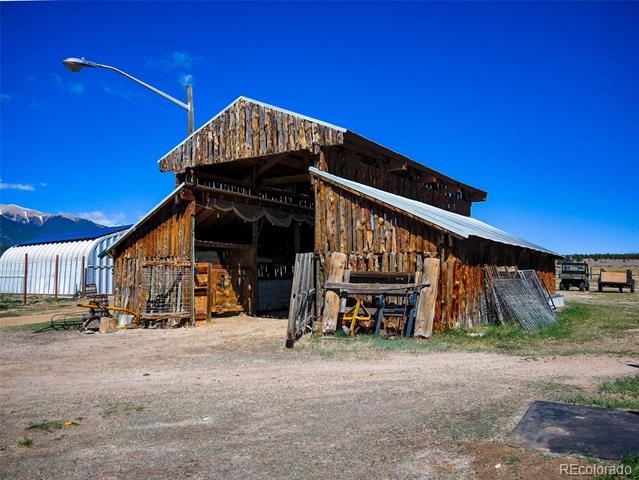 Weathered wooden barn with open entrance and attached lean-tos in a rural yard.