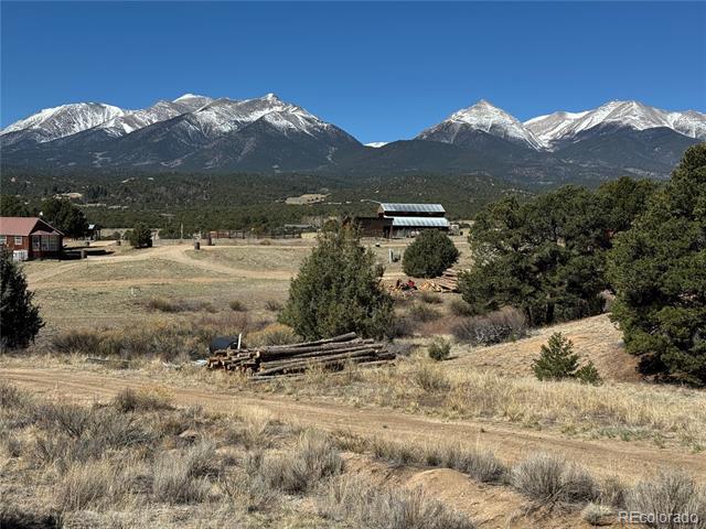 Rural property with scattered buildings and dry grassland below snow-capped mountains.