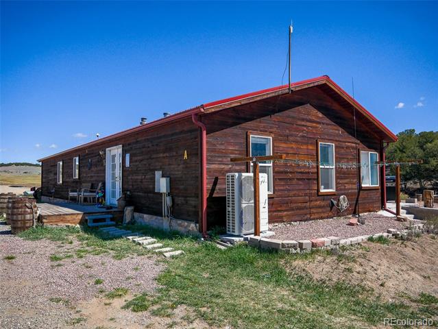 Rustic wood-sided property with a red metal roof and gravel yard.