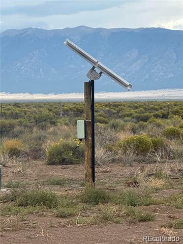 Open scrubland with a solar-panel-topped post and mountains in the distance.