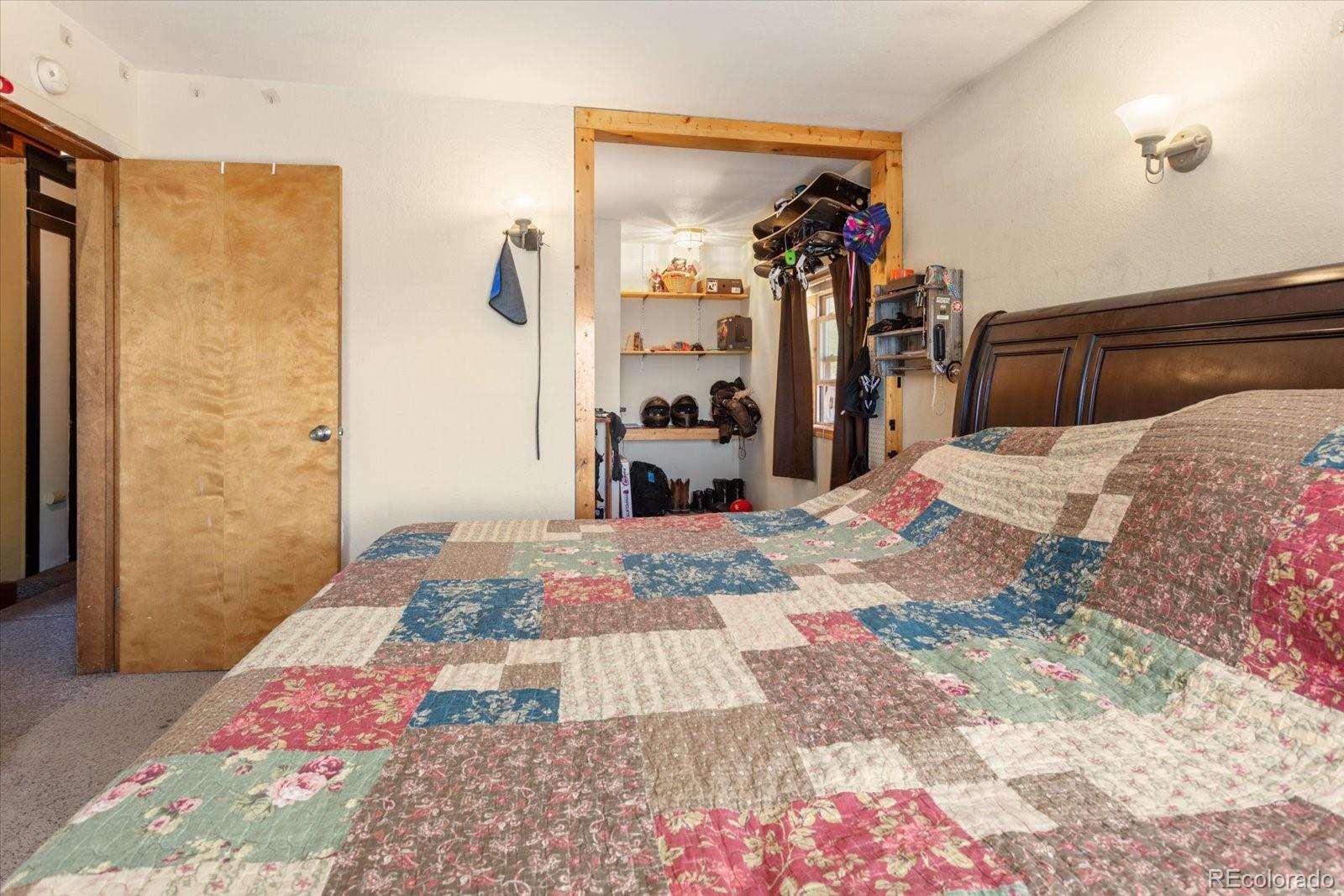 Bedroom with a colorful patchwork quilt and an open doorway to a storage area.