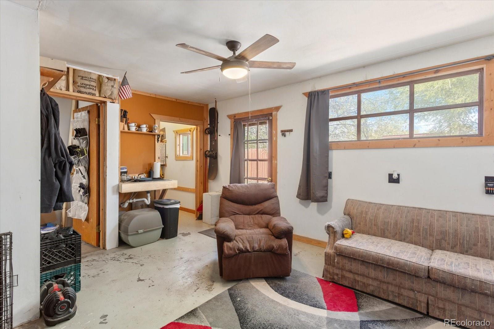 Living room with a brown recliner, patterned sofa, ceiling fan, and large windows.