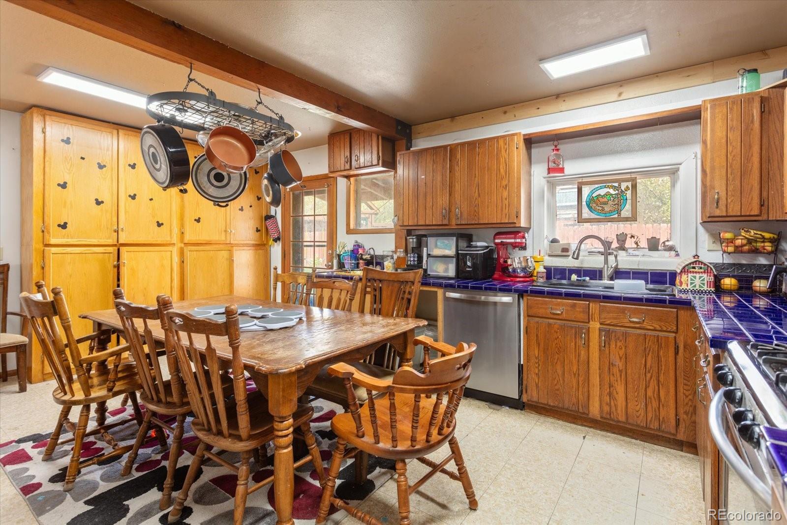 Kitchen with wood cabinets, blue tile countertops, and a dining table beneath hanging cookware.
