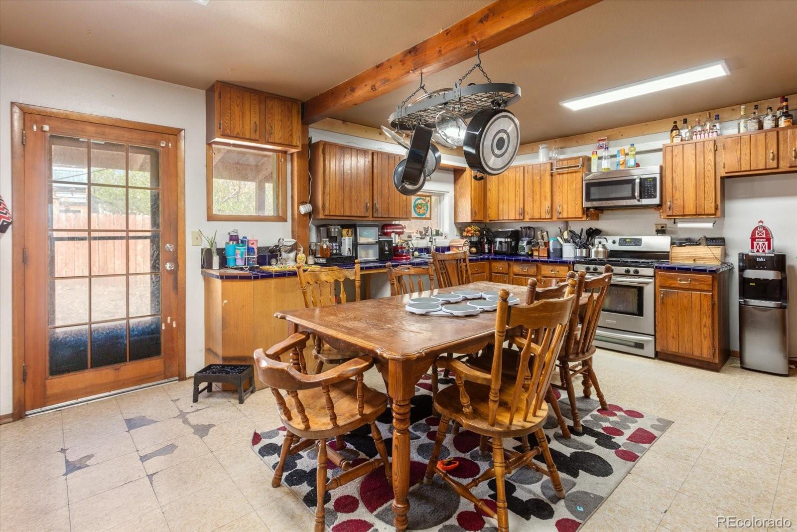 Kitchen and dining area with wood cabinets, a large dining table, and hanging pot rack.