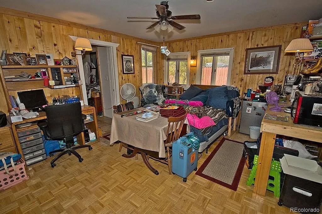 Wood-paneled living room with a sofa, dining table, and desk area.