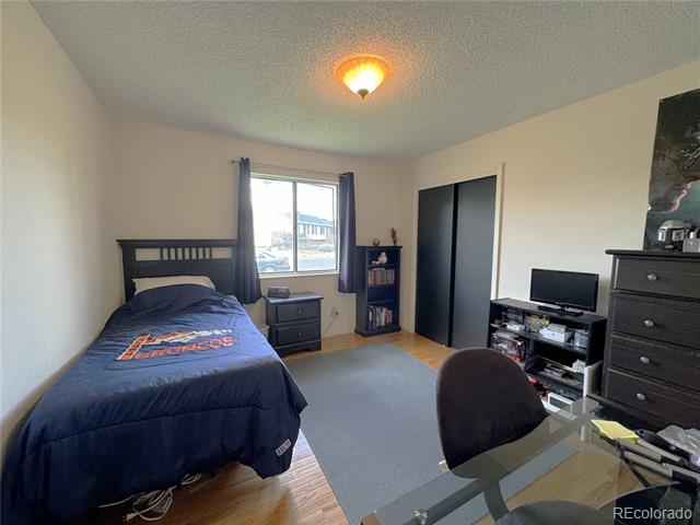 Bedroom with a single bed, Broncos blanket, dark curtains, and sliding closet doors.