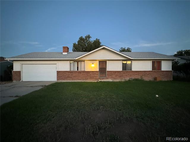 Single-story home with attached garage, brick lower facade, and broad front lawn.