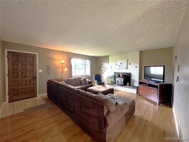 Living room with a brown sectional, brick fireplace, and wood floors.