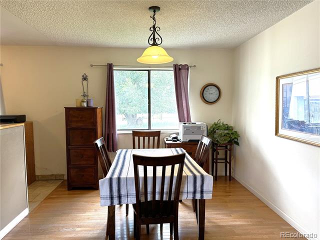 Dining room with a striped tablecloth, dark wooden chairs, and daylight through two windows.