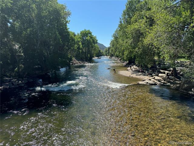 River flowing over rocks between wooded banks, with a person standing in the shallow water.