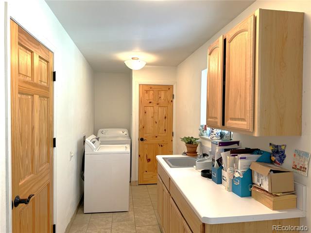 Laundry room with a white washer, wood cabinets, and a long counter with an inset sink.