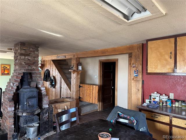 Rustic room with a black wood stove in a brick fireplace and exposed timber framing.