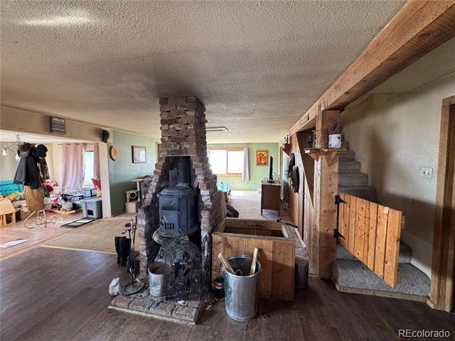 Living area with a brick chimney and black wood stove beside a wood-paneled staircase.