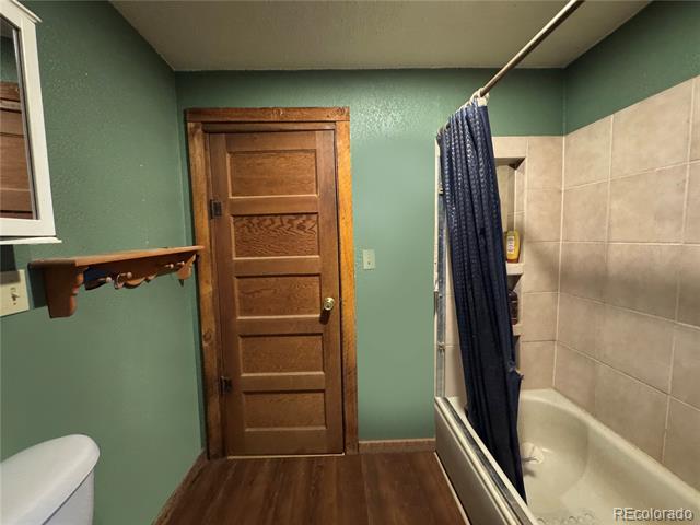 Bathroom with a white tub, dark blue shower curtain, beige tile, and green walls.