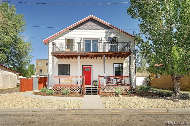 Two-story white house with red trim, a red front door, and an upper balcony.
