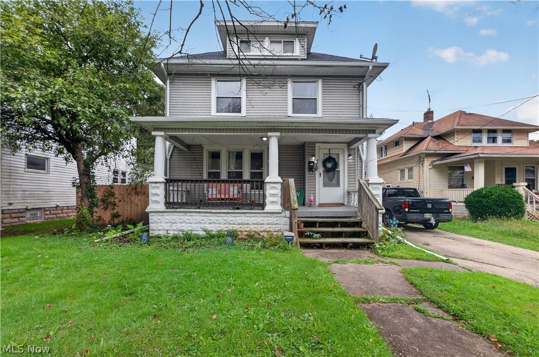 Gray two-and-a-half-story house with a covered front porch and small lawn.
