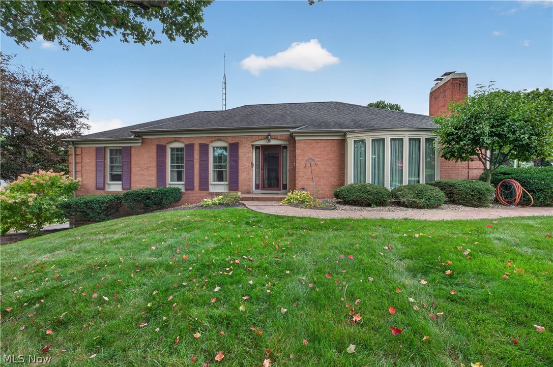 Red brick house with purple shutters, large windows, and an autumn-leaf-strewn lawn.